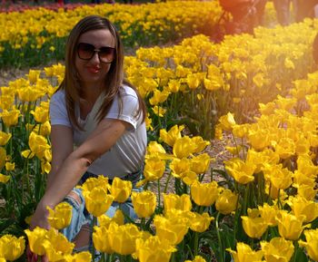 Young woman standing by yellow flowers on field