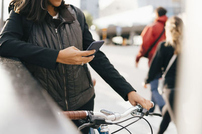 Rear view of people using mobile phone in city