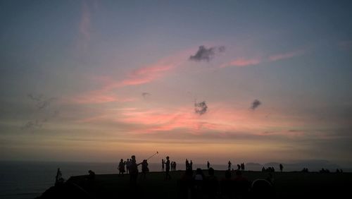 Silhouette people on beach against sky during sunset