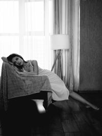 Portrait of young woman sitting on sofa at home