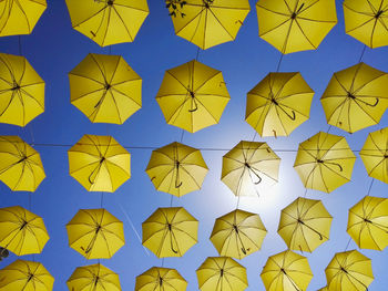 Low angle view shot of yellow umbrellas hanging against sky