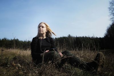 Young woman with dog on field against sky