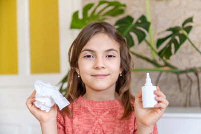 Portrait of girl with nasal spray and tissue sitting at home