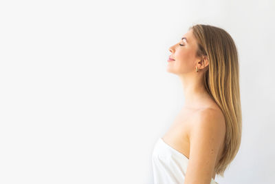 Portrait of smiling young woman standing against white background