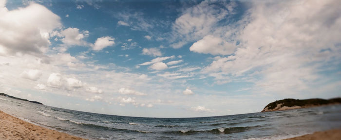 Fish-eye view of sea against cloudy sky