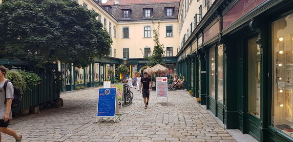 Rear view of woman walking on street amidst buildings