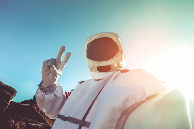 Low angle view of astronaut gesturing against sky