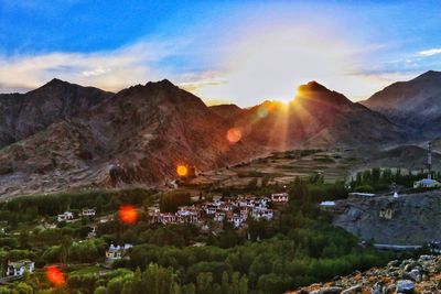 Scenic view of townscape and mountains against sky at sunset