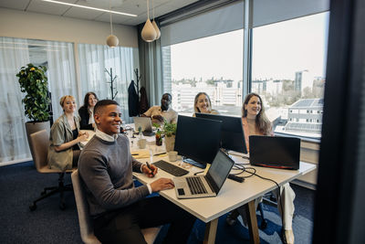 Smiling male and female business colleagues during video conference in coworking office