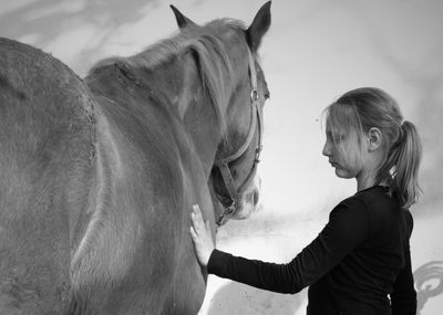 Young woman standing by horse against sky