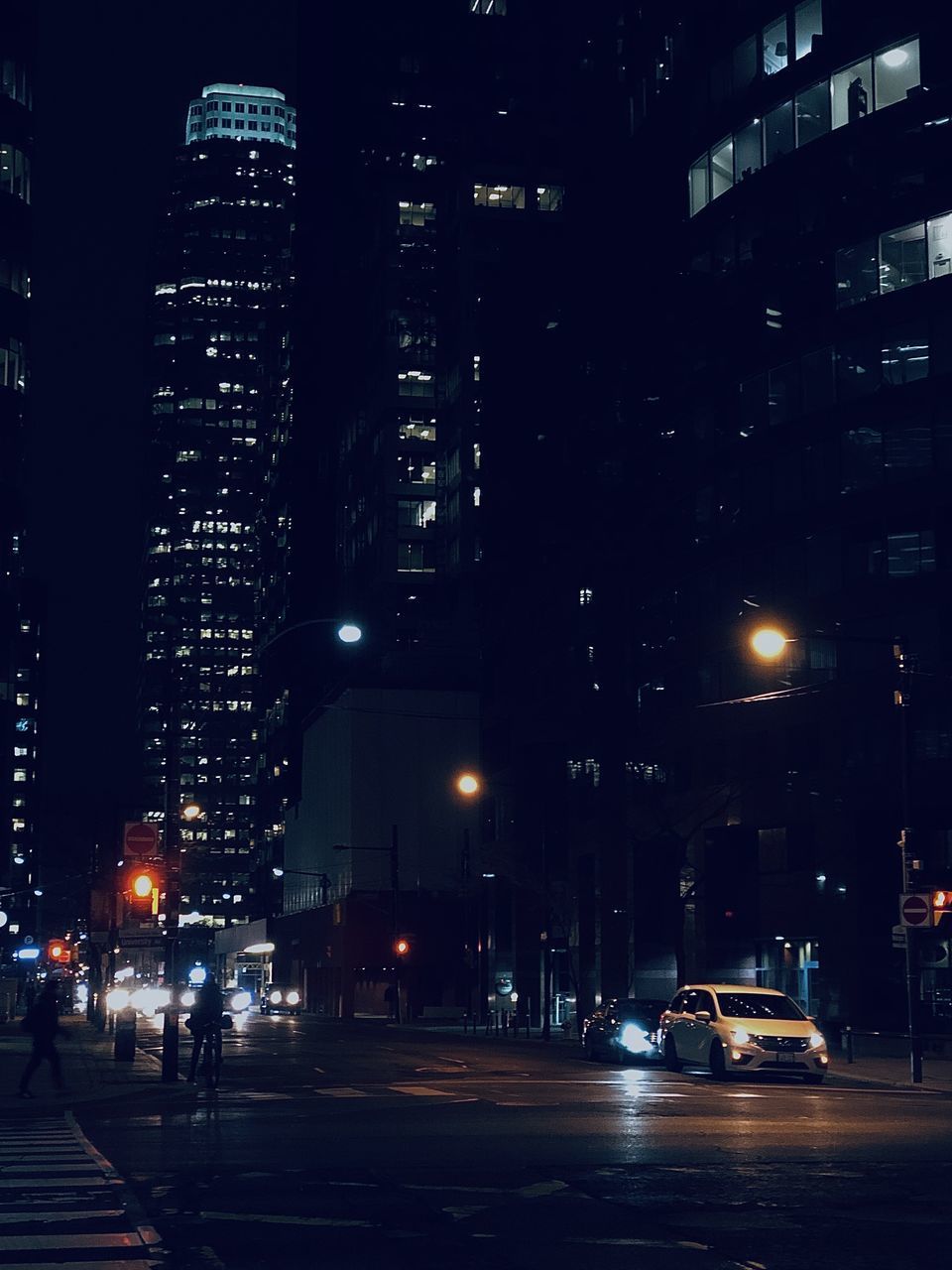 CITY STREET BY ILLUMINATED BUILDINGS AT NIGHT