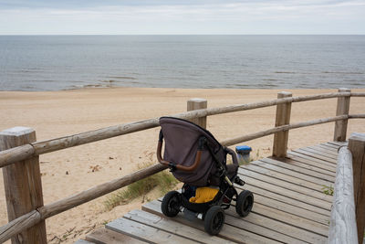 Baby stroller on boardwalk against sea