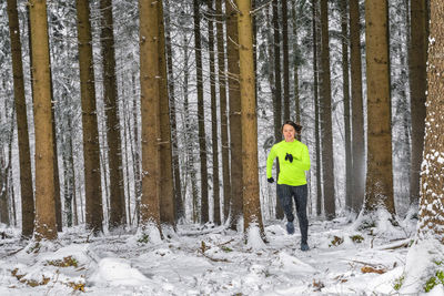 Man standing amidst trees in forest during winter