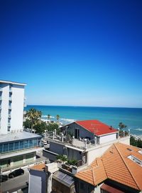 High angle view of houses by sea against clear blue sky