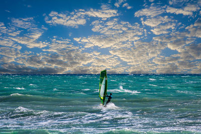 Person windsurfing in sea against sky