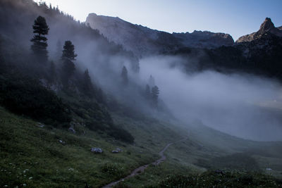 Scenic view of mountain against clear sky in foggy weather