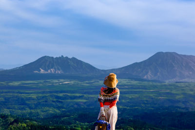 Rear view of woman standing on mountain against sky