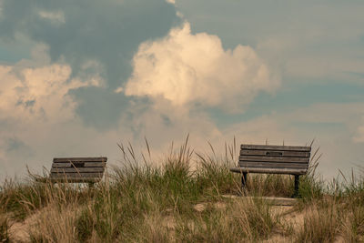 Empty bench on field against sky