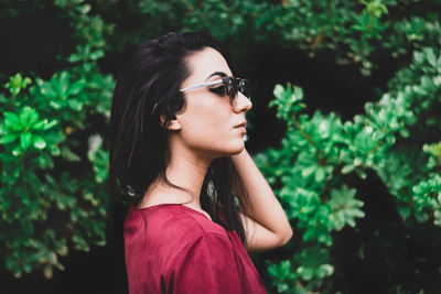 Close-up of young woman looking away against trees