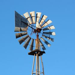 Low angle view of american-style windmill against clear blue sky