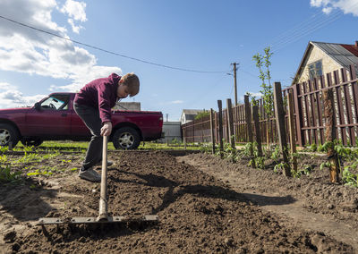 Man working on agricultural field against sky