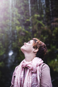 Young woman standing against trees in forest