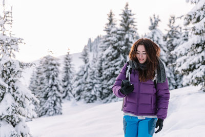 Portrait of young woman standing on snow covered field