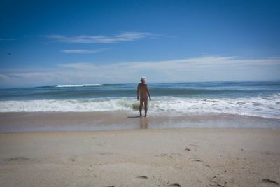 Rear view of nude man on beach against sky