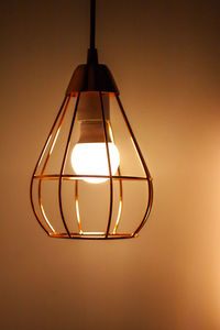 Close-up of illuminated light bulb hanging from ceiling