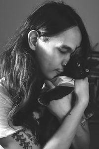 Close-up of man embracing cat while standing at home