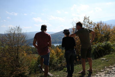 Rear view of men and son on land against sky