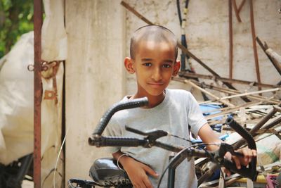 Portrait of boy with bicycle standing outdoors
