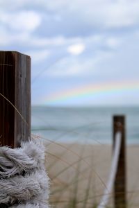 Close-up of wooden posts in sea against sky