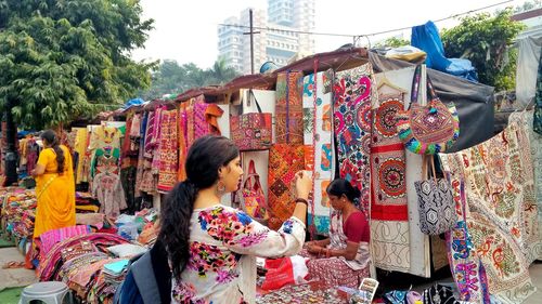 Young woman looking at earring while standing at market stall