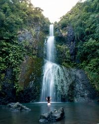 Man looking at waterfall in forest