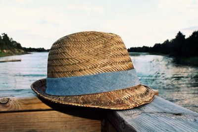 Straw hat on wooden railing against lake