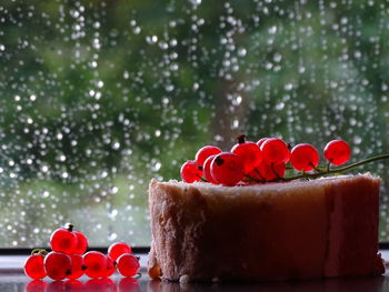 Cake with red currant berries on the background of a window in raindrops