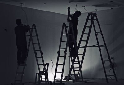 Silhouette people working on wall