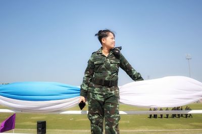 Female soldier standing against blue sky