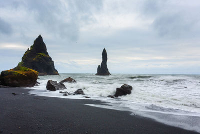 Rock formation on beach against sky