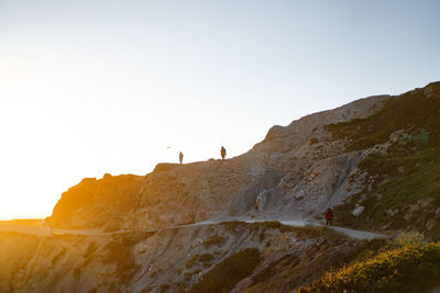 Low angle view of people on mountain against clear sky