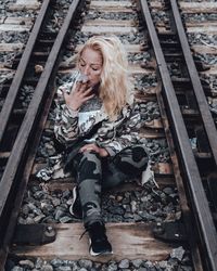 Young woman sitting on railroad track