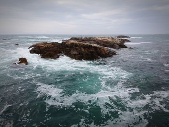 Rocks in sea against sky