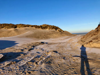 The shadow of the photographer is falling over the sand of the dunes he is photographing