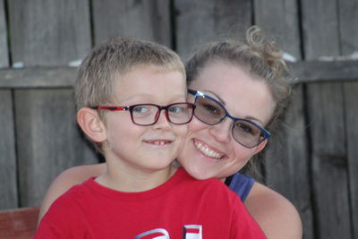 Portrait of smiling mother and son wearing eyeglasses at backyard