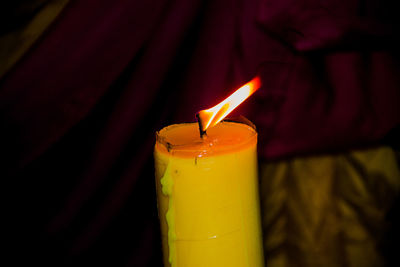 Close-up of lit candle in the dark