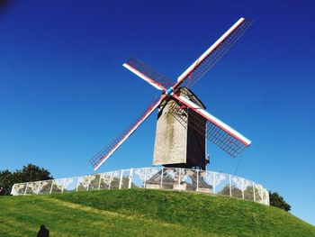 Traditional windmill on field against clear blue sky