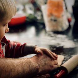 Cropped hand of father with son making food at kitchen island