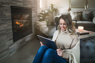 Smiling young woman using digital tablet while sitting at home