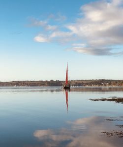 Red sail seen in the distance. river fal in cornwall , the most southerly county of the uk.